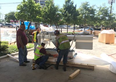 Men wrapping a large piece of medical equipment to prepare for shipping.